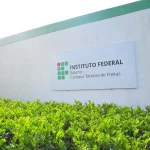 Fachada de prédio do IF Baiano em Teixeira de Freitas. Ao centro da imagem, uma placa com a logo da instituição.